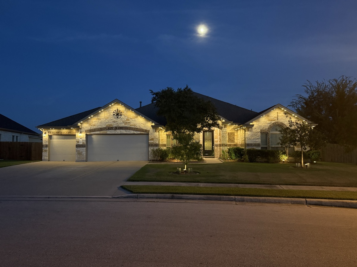 Austin Hill Country home with TruLight 48-volt permanent LED lighting along the entire roofline at night