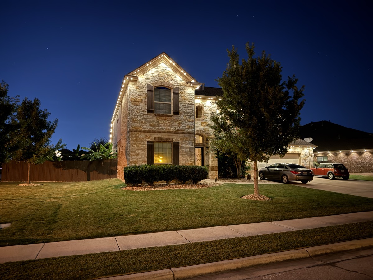 Limestone Austin home with TruLight 48-volt permanent lighting at dusk