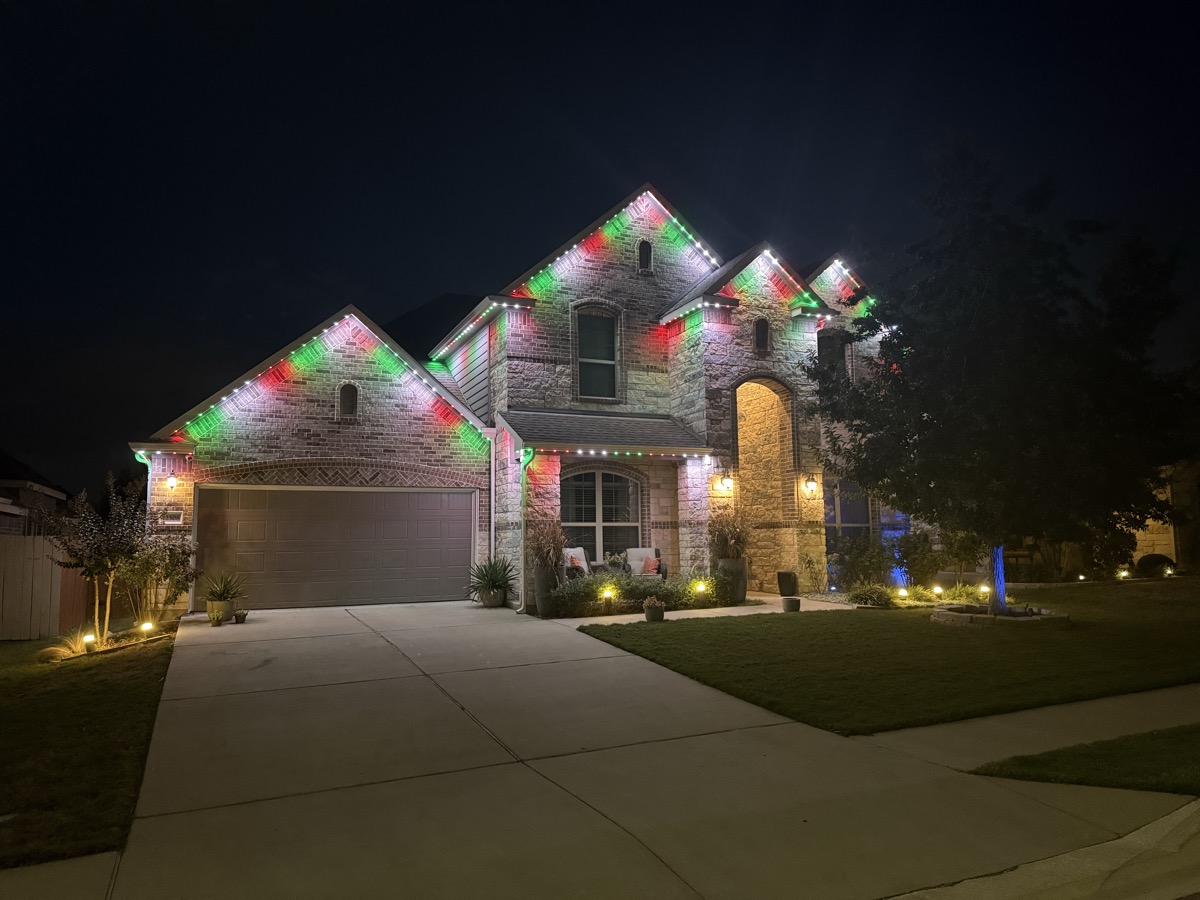 Austin two-story stone home with permanent motion sensor LED lighting across the roofline at night